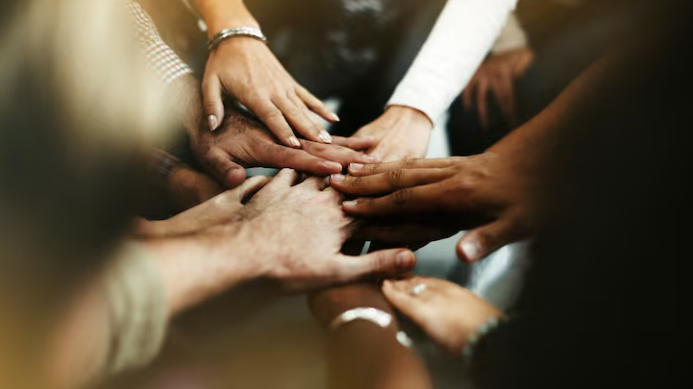 A team with hands piled into a circle.